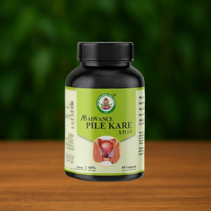 A bottle labeled Ayur Brahma Pile Kare X Plus with a green and yellow label rests on a wooden surface against a blurred green background. The label displays a diagram and information about the capsules.