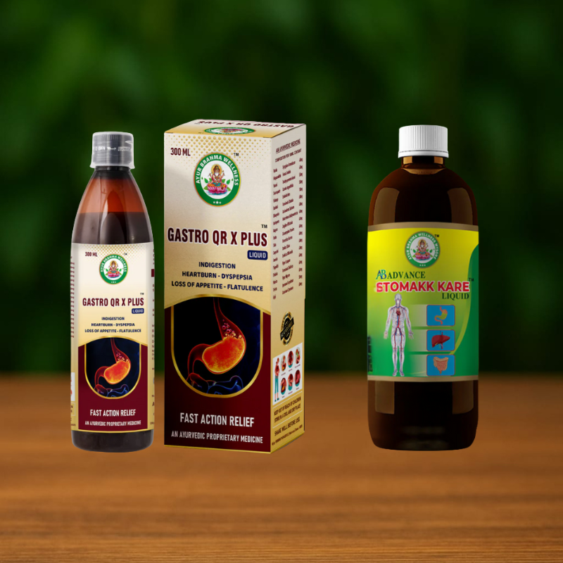 Two bottles of liquid medicine and a box labeled Stomakk Kare & Gastro QR X Plus Combo, featuring digestive relief benefits, are displayed on a wooden surface with a blurred green background.