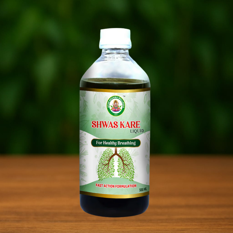 A 500 mL bottle of Ayur Brahma Advance Shwas Kare for healthy breathing rests on a wooden surface, featuring a green leafy lung illustration and a blurred green background.