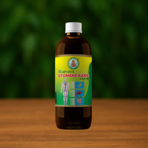 A brown bottle with a white cap labeled Ayur Brahma Advance Stomakk Kare Liquid stands on a wooden surface, featuring a label with a human figure and digestive system illustrations against a green blurred background.